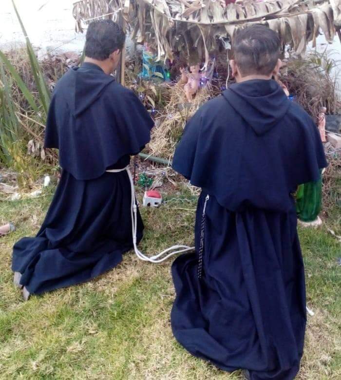 Frati in preghiera davanti al presepe all'aperto